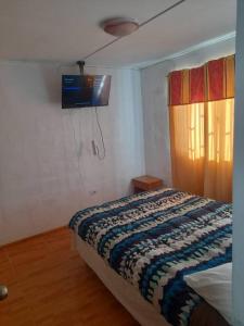 a bedroom with a bed and a tv on the wall at arriendo casa para 6 personas in Caldera