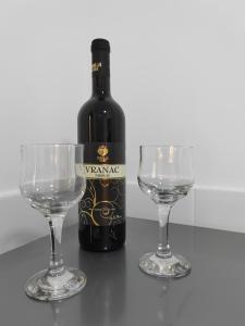 a bottle of wine and two wine glasses on a table at Apartman SM in Sremska Mitrovica