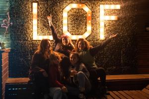 un grupo de chicas sentadas frente a un cartel con la palabra boo en LÖF Hostal, en Pichilemu