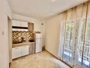 uma cozinha com um frigorífico branco e uma janela em Aniva Apartments em Šušanj