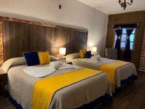 Habitación de hotel con 2 camas con sábanas amarillas en Hotel El Aguila en Villa del Carbón