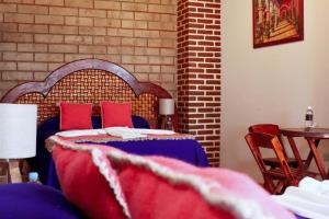 1 dormitorio con 1 cama con almohadas rojas y pared de ladrillo en Hotel El Aguila en Villa del Carbón
