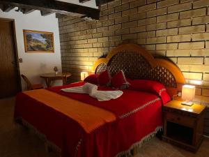 1 dormitorio con cama roja y pared de ladrillo en Hotel El Aguila en Villa del Carbón