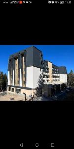 a large building with a black and white building at Apartman Vuk, Apart hotel Zlatni javor in Jahorina