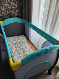 ein Kinderbett mit einem Bett in einem Zimmer in der Unterkunft Vrnjačka Romansa Studio - Pešačka zona - Ravni deo - Baby friendly in Vrnjačka Banja