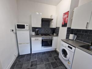 eine kleine Küche mit einem weißen Kühlschrank und einem Geschirrspüler in der Unterkunft Primos Castle - 1 Bedroom in North Shields in North Shields