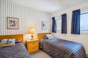 two beds in a bedroom with blue curtains at Spacious & cheerful Pico slopeside Condo Walk to lift & ski back! Pico 304 in Killington