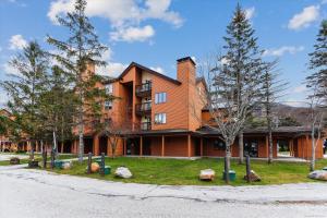 a large brick building with trees in front of it at Charming 2-Bedroom Slopeside at Pico Mountain E304 in Killington
