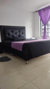 Cama en habitación con cortina púrpura en Casa la camelia en Manizales