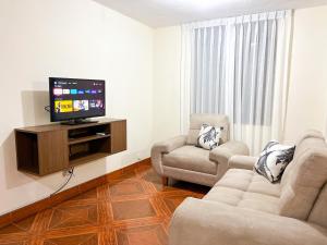sala de estar con 2 sillas y TV de pantalla plana en Departamento completo a minutos de playas, en Barranca
