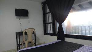 1 dormitorio con 1 cama, 1 silla y 1 ventana en Casa la camelia en Manizales