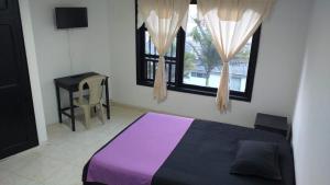 1 dormitorio con 1 cama de color púrpura y 2 ventanas en Casa la camelia en Manizales