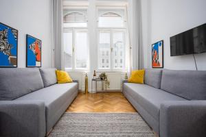 een woonkamer met twee grijze banken en een televisie bij Bohémien Apartment in Boedapest