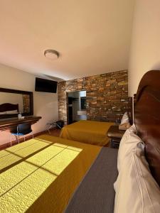 una camera d'albergo con due letti e una parete in pietra di Hotel Colonial de Nogales a Nogales