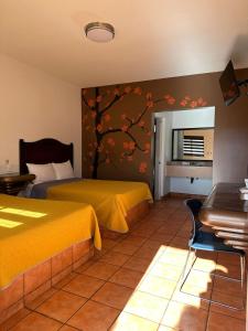 a bedroom with two beds and a tree mural on the wall at Hotel Colonial de Nogales in Nogales