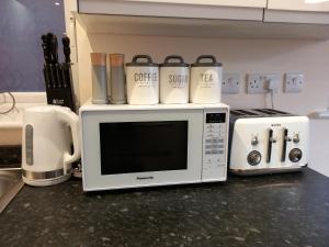 a microwave oven with coffee cups on top of it at Modern large 2 Bed whole apartment - Free parking - Ground floor - Central Beeston in Nottingham