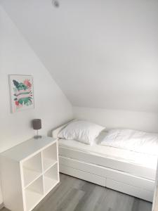 - un lit blanc dans une chambre blanche avec une table dans l'établissement Ferienhaus Mila 70qm bis 5 Gäste mit Fass-Sauna, Whirlpool April bis Oktober, 75qm Terrasse und eingezäunten Garten Haustiere willkommen, à Sierosław
