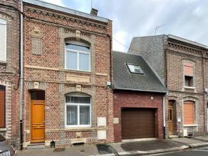 a brick building with a garage and a brown door at Charming City Home Near Downtown with Garage in Amiens
