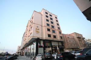 un edificio alto con auto parcheggiate in un parcheggio di فندق قصر توبال للشقق المخدومة a Gedda