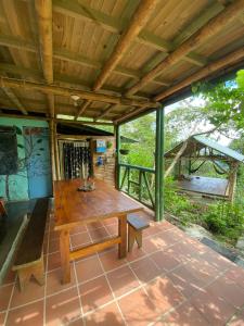 einen Holztisch und eine Bank auf einer Terrasse in der Unterkunft Ecofinca in the mountains Azulita House in Cocorná