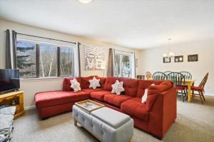 a living room with a red couch and a tv at Spacious Northbrook 3 townhouse only 2 miles from restaurants & nightlife in Killington