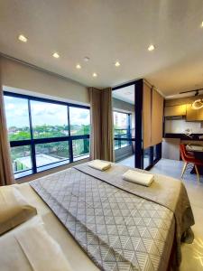 a bedroom with a large bed and large windows at Vertigo Premium Studios - Luxo e Praticidade in Campo Grande