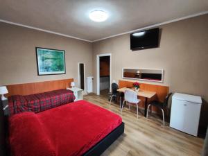 1 dormitorio con cama roja y mesa con sillas en B&B Bella Garbatella, en Roma