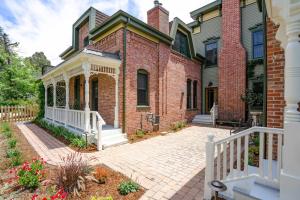 ein Backsteinhaus mit einer Veranda und einem weißen Zaun in der Unterkunft Captivating Cowgirl in Denver