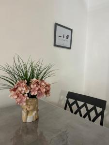 B&B Queen's Luck في إيركولانو: مزهرية مع الزهور الزهرية تقف على طاولة