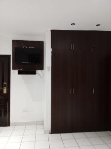 a kitchen with black cabinets and a flat screen tv at HOTEL DORAL in Guayaquil
