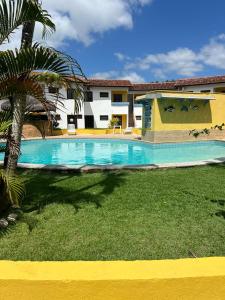 a swimming pool in front of a house with a palm tree at Apartamento inteiro n.24 in Porto Seguro