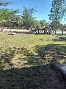 ein großes Grasfeld mit einem Zaun und Bäumen in der Unterkunft rafaella in Villa Anizacate
