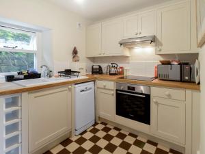 a kitchen with white cabinets and a checkered floor at Ivy Cottage - Uk42246 in Broughton