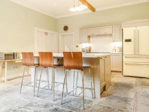 a kitchen with white cabinets and bar stools at The Manse - Uk42249 in Broughton