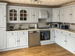 a white kitchen with white cabinets and appliances at Beach Croft in Brora