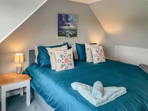 um quarto com uma cama azul e uma mesa de madeira em Beach Croft em Brora