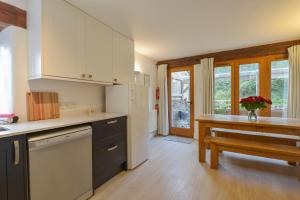 cocina con armarios blancos y mesa de madera en Fixit Cottage en Kingsbridge