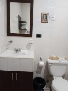 a bathroom with a white toilet and a sink at HOTEL DORAL in Guayaquil