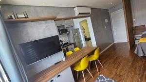 a small kitchen with a table and yellow chairs in a room at Dias na Praia in São Vicente