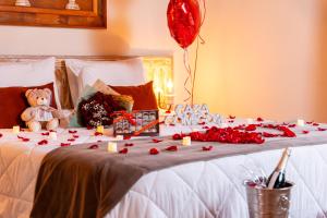 a bed with roses and a teddy bear and balloons at Pousada Cerejeiras in Monte Verde