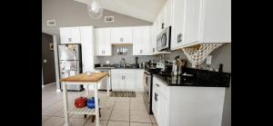 ガルフ・ショアーズにあるFamily Friendly Home in walking district, 5 minutes from beachの白いキャビネットと木製のテーブルのあるキッチン