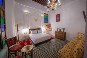 a bedroom with a bed and a couch and a chandelier at Riad Soultan in Fès +287 photos