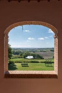 une fenêtre en voûte avec vue sur un champ avec bancs dans l'établissement Villa Santa Virginia, à Sienne