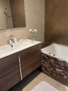 Luxury Apartement Near the Beach في Sidi Bouqnadel: حمام مع حوض وحوض استحمام مع إناء من الزهور