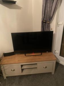 TV de pantalla plana en la parte superior de un centro de entretenimiento de madera en Lovely 2nd floor 2 bed flat sleeps 4, en Doncaster