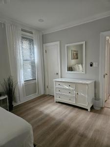 a white bedroom with a dresser and a mirror at Brooklyn retreat 1 in Brooklyn