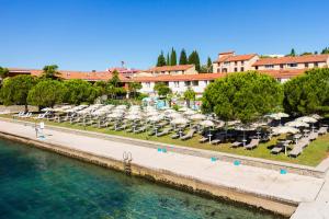 un gruppo di sedie e ombrelloni accanto all'acqua di Hotel Histrion a Portoroz