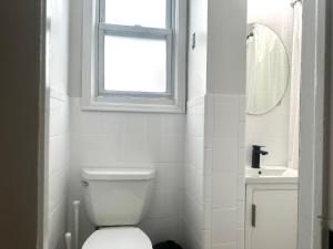 a white bathroom with a toilet and a window at 2-A Diamond in Yonkers in Yonkers