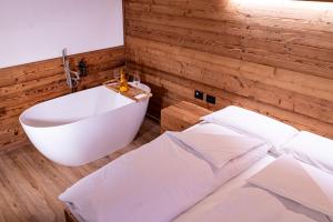 a bathroom with a white tub and a bed and a bath tub at Chalet Baita del Sole in Teglio