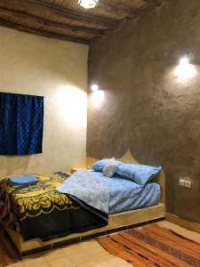 um quarto com uma cama com lençóis azuis e almofadas azuis em DAR AMMAR em Merzouga